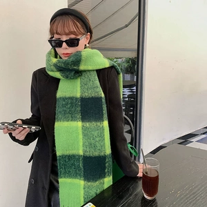 Thick green and black checkered mohair scarf with braided fringe worn by model outdoors