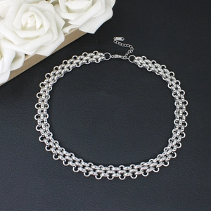 Detailed close-up of a silver braided chain necklace with lobster clasp on black background
