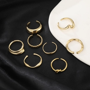 Set of 8 gold minimalist rings with woven and bamboo textures on black silk and white ceramic
