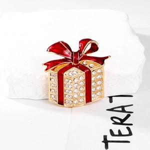 Sparkling Christmas gift box brooch with red enamel bow and crystals on white marble