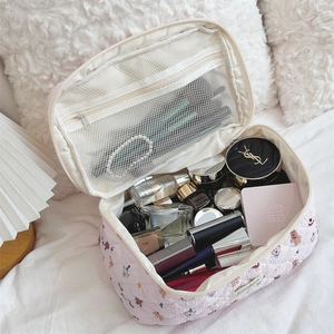 Pink quilted makeup bag with bear pattern showing internal mesh pocket and cosmetics