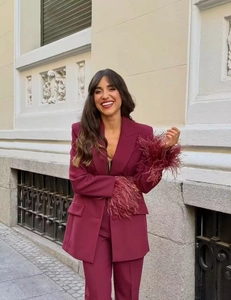 Dettaglio di tailleur bordeaux da donna con eleganti piume sui polsini e tessuto fluido