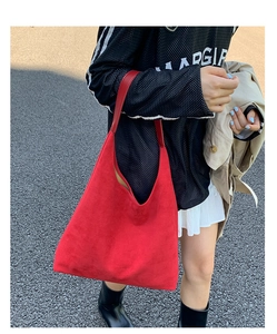 Close-up of red suede tote bag texture and spacious interior carried by a model outdoors