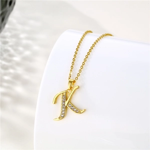 Macro detail of 18K gold plated letter K pendant with sparkling cubic zirconia inlay