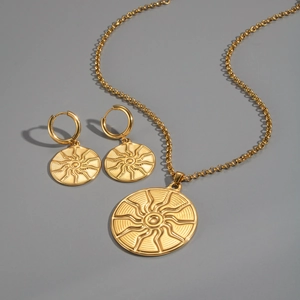 Set gioielli dorati con rilievo a sole, collana rotonda e orecchini a cerchio su sfondo grigio