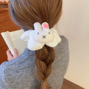 Close-up of white polka dot plush hair tie with cute rabbit character and pink button details