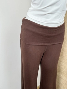 Close-up of brown ribbed knit trousers with a stylish fold-over waistband detail