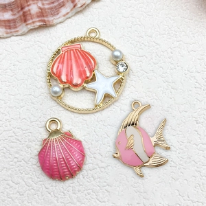 Macro shot of pink sea star, shell and tropical fish charms for DIY jewelry making