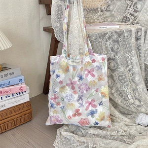 Detailed shot of mesh shoulder bag with floral prints and brand label on a lace cloth