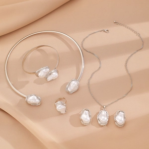 Detailed set of silver baroque pearl jewelry with necklace, bracelet and ring on beige fabric