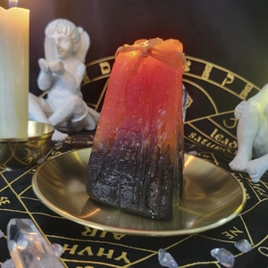 Close-up of square pyramid candle with wax drips on mystical altar metal plate
