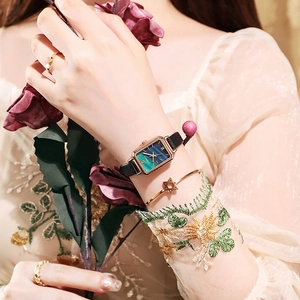 Close-up of vintage square gold watch with green malachite dial and black leather strap