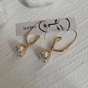 Minimalist gold geometric twist earrings with white pearl accents on white background