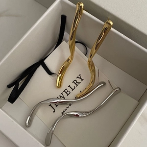 Orecchini pendenti ondulati in metallo oro e argento su elegante scatola da regalo