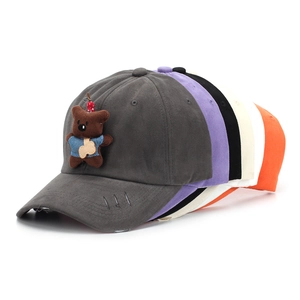 Close-up of distressed baseball caps with cute bear patch and torn brim detail