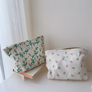 Close-up of floral cotton cosmetic bags with Simple Wish label on white books
