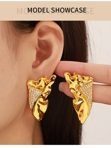 Detail of vintage geometric textured gold wing earrings with rhinestones on model ear