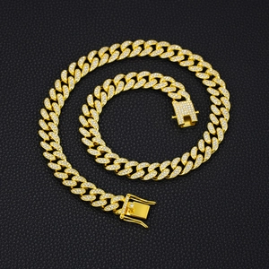 Macro shot of gold-plated 13mm Cuban link necklace with sparkling crystals on black leather