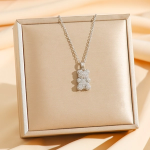 Collar con colgante de oso brillante y circonitas blancas sobre caja de regalo de seda