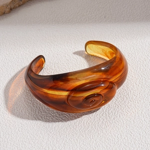 Macro shot of an amber acrylic cuff bracelet featuring a unique spiral vortex pattern