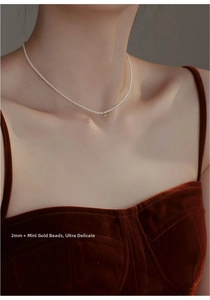 Detail of a dainty 2mm freshwater pearl choker necklace with a small 14K gold-filled bead