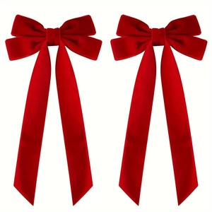Close-up detail of a pair of red velvet double bow hair accessories with long ribbons