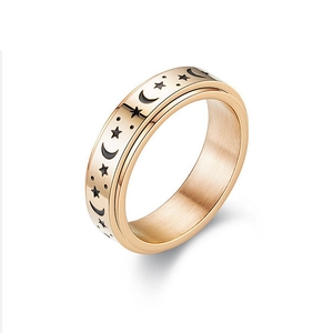 Macro view of rose gold spinner ring featuring moon and star black enamel details