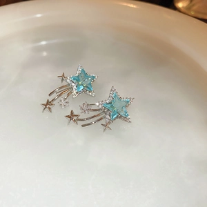Close-up of shooting star earrings with light blue star crystals in a ceramic dish