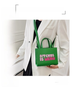 Detail of green structured leather handbag featuring bold pink lettered print design