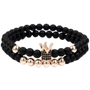Detail of beaded bracelets featuring black matte stones and a rose gold crown charm