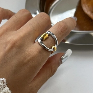 Close-up of two-tone gold and silver horseshoe buckle ring on female hand