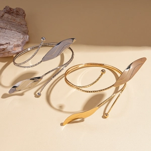 Elegant gold and silver leaf spiral arm cuffs with textured vein details in a minimalist set