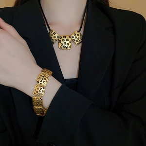 Nahaufnahme von goldenem Halsketten- und Armband-Set mit Leopardenmuster im Vintage-Stil