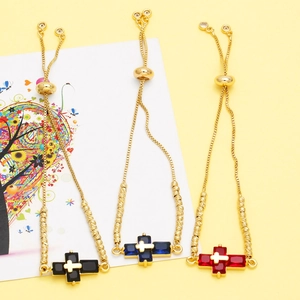 Detailed shot of gold-plated cross charm bracelets with blue black and red stones