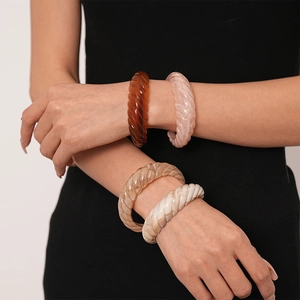 Stacked vintage acrylic resin twisted bangles in amber, pink marble, and tan shades