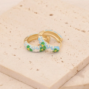 Macro shot of gold enamel flower earrings with blue and white petals on a stone base