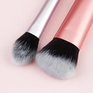 Detail of rose gold and silver makeup brushes with fluffy black and white ombre bristles