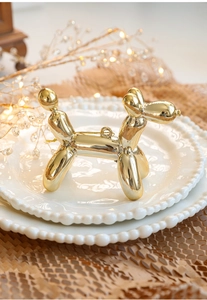 Detailed view of a golden balloon dog ornament with mirror finish on a decorative plate
