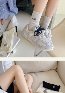 Detailed close-up of white knitted crew socks with embroidery worn with casual sneakers