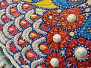 Macro detail of 5D diamond painting with colorful resin rhinestones on peacock pattern