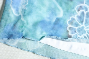 Close-up of light blue printed mesh fabric detail with fine stitching and dual-layer lining