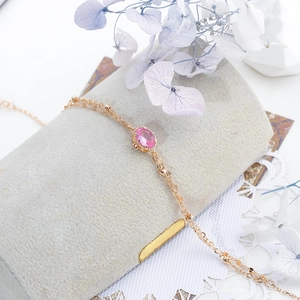Detail of rose gold double-layer bracelet with pink oval stone and small beads