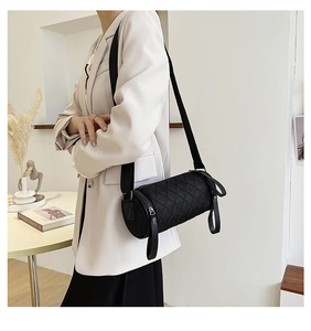 Detail showing black quilted cylindrical crossbody bag with rhombus pattern on model