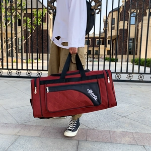 Outdoor shot of a foldable burgundy Oxford fabric travel bag with reinforced handles