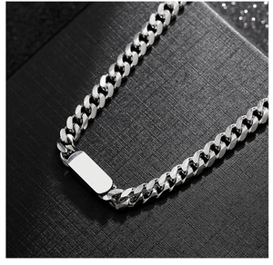 Macro view of silver cuboid pendant on polished stainless steel cuban link necklace