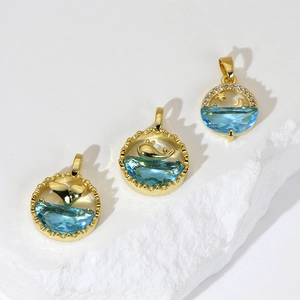 Gold dolphin and whale tail ocean pendants with blue zircon on white stone base