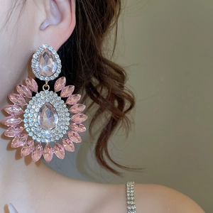 Detail view of oversized pink crystal flower earrings worn by a model in soft light