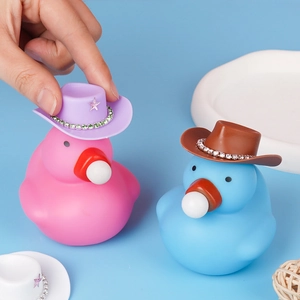 Pink and blue rubber ducks wearing decorative cowboy hats with rhinestones on a blue surface