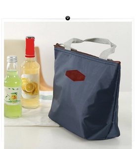 Detail of navy waterproof nylon lunch bag with grey handle and brown leather badge