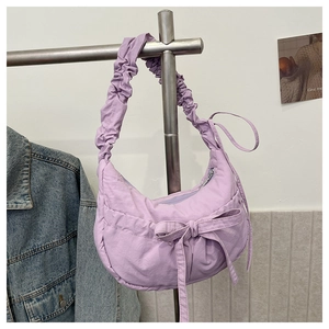 Detail of purple nylon crescent bag featuring pleated shoulder strap and bow decoration